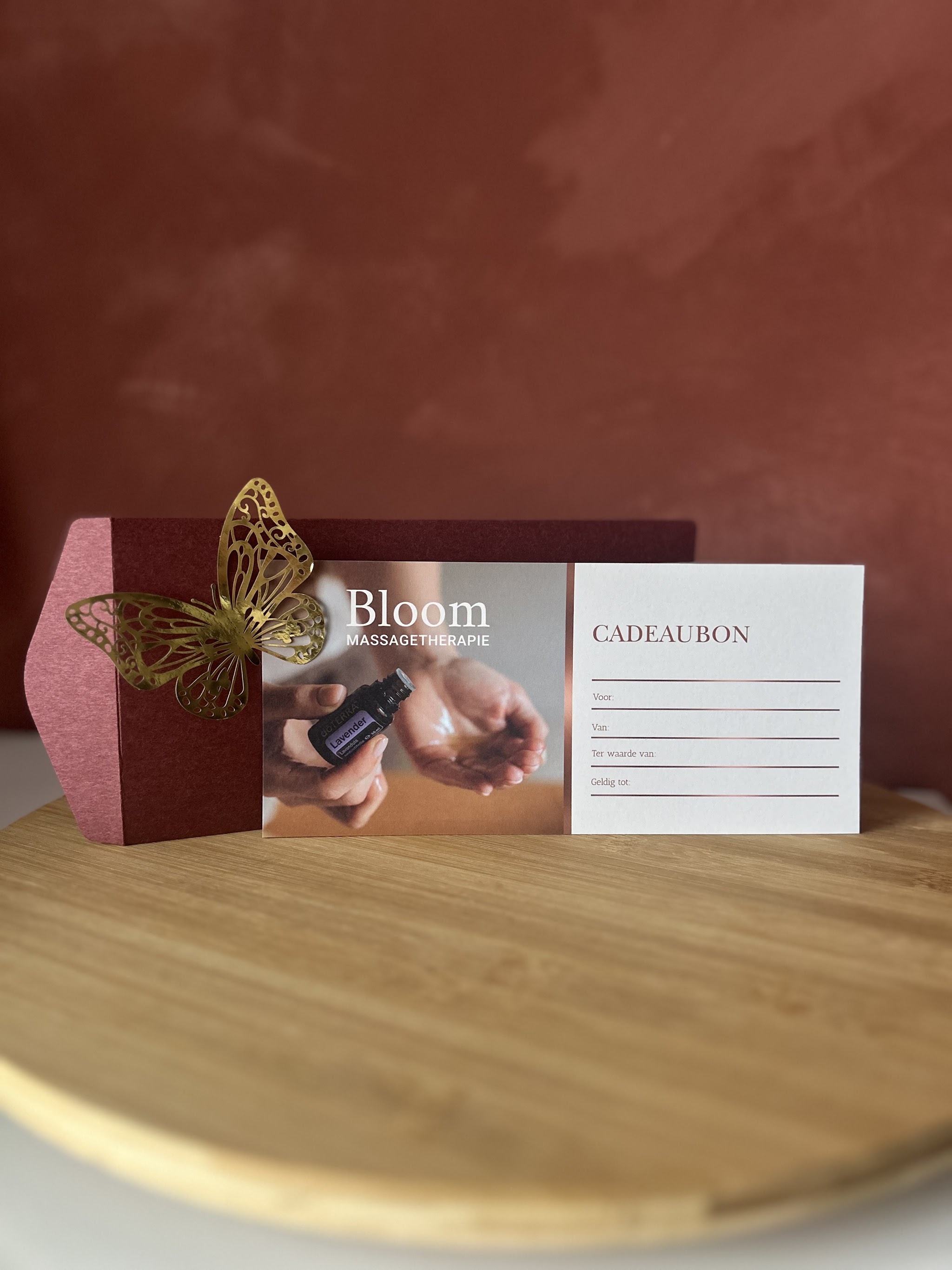Cadeaubon van Bloom massage therapie met een gouden vlinder, op een houten plank