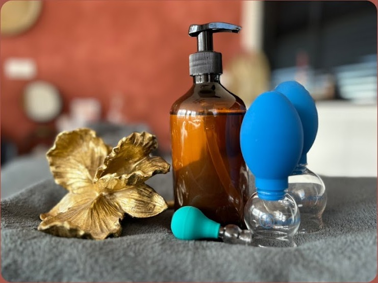 Massageolie, een gouden bloem en cupping cups op een grijze doek